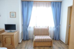 um quarto com uma cadeira, uma televisão e cortinas azuis em Hotel Sternen em Aarau