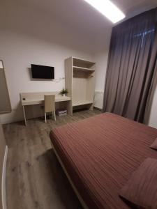 Dormitorio con cama, escritorio y TV en B&B LEI, en Foggia