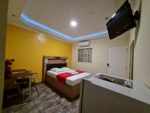 a bedroom with a bed and a desk and a television at PENSEENTRE MOTEL in Rio Claro