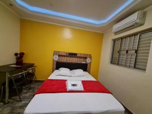 a bedroom with a bed with a red blanket and a desk at PENSEENTRE MOTEL in Rio Claro