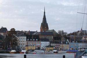 a group of buildings with a clock tower in a city at Sunday Hotel Flensburg in Flensburg