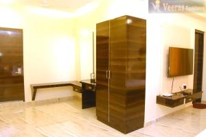 a bathroom with a large wooden cabinet and a television at Veeras Residency in Pondicherry