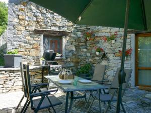 a patio with a table and chairs and a stone wall at Apartment Open Space with Patio Lety by Interhome in Malvaglia