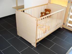 ein Kinderbett mit einem Teddybären in einem Zimmer in der Unterkunft Apartment Burn- Alte Strasse by Interhome in Adelboden