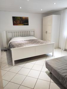 a bedroom with a white bed and a white tiled floor at Ferienwohnung Waldblick Teutoburger Wald in Oerlinghausen