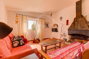 a living room with a red couch and a fireplace at Villas2go2 Praia da Marinha in Lagoa
