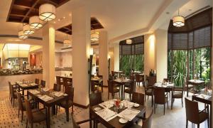 a dining room with tables and chairs and windows at The Leela Mumbai in Mumbai