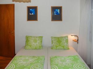 sypialnia z łóżkiem z zielonymi i białymi poduszkami w obiekcie Apartment REX by Interhome w mieście Muralto