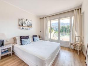 - une chambre avec un grand lit blanc et une fenêtre dans l'établissement Apartment Le Val Riant by Interhome, à Cannes
