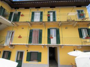 a yellow building with green windows and balconies at Apartment White by Interhome in Germignaga