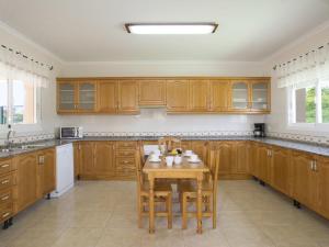 a kitchen with wooden cabinets and a table with chairs at Villa Nadaltenis by Interhome in Calpe