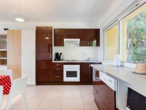 eine Küche mit braunen Schränken und einer weißen Arbeitsplatte in der Unterkunft Apartment Les Coccinelles by Interhome in Cavalaire-sur-Mer
