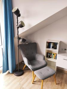a room with a chair and a lamp and a book shelf at 5D Apartament przy Plaży in Grzybowo