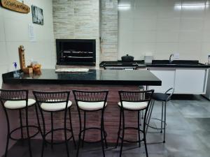 a kitchen with a counter with four bar stools at Casa temporada Beto Carrero in Penha