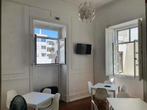 a dining room with two tables and two windows at Baixa Terrace Hostel in Faro