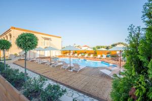 a swimming pool with lounge chairs and umbrellas at Nuevo Vista in Kavos