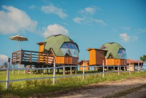 Reserva Campestre LA CABAÑA GLAMPING في دويتاما: مجموعة منازل ذات سطوح خضراء على ميدان