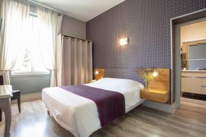 Rúm í herbergi á Logis Hotel L'Occitan 2 étoiles