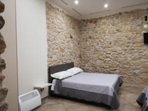 a bedroom with a bed and a stone wall at B&B Del Borgo in San Marco Argentano