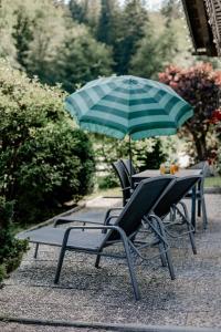 einen Tisch und Stühle mit Sonnenschirm auf einer Terrasse in der Unterkunft Der Lärchenhof Ferienwohnungen in Schönau am Königssee