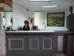 a woman standing at a counter in an office at Hotel Don Carmelo in Avila