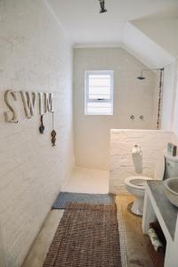 a white bathroom with a sink and a toilet at The Crowded House in Pringle Bay