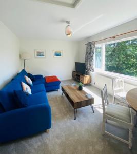 uma sala de estar com um sofá azul e uma mesa em Eagle House Holiday Let em Bude