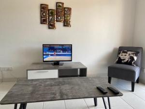 een woonkamer met een tv en een tafel en een stoel bij Apartment Iris Village Kato Paphos in Paphos