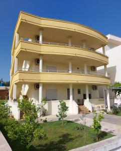 a large yellow building with trees in front of it at Korac Apartments in Ulcinj