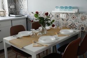 einem weißen Tisch mit Platten und einer Vase mit roten Rosen in der Unterkunft Apartman 3 in Komárom