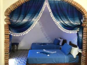 duas camas num quarto com cortinas azuis em Hotel Nisrine em Chefchaouene