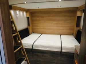 a bed in a small room with a wooden wall at Chapel Fields Holiday Park in Chapel Saint Leonards