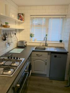 uma pequena cozinha com um fogão e um lavatório em Lovely well equipped apartment - 2 bedroom, sleeps 4, sundeck, 8 min river walk to beach and town, FREE parking permit ! em Lyme Regis