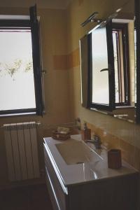een badkamer met een wastafel, een spiegel en een raam bij Le Radici Laviano in Laviano