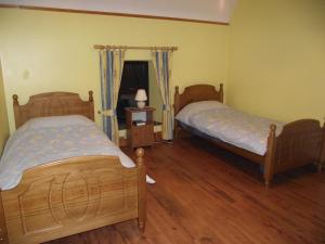 two beds in a room with wooden floors at Pine View Self Catering Holiday Home in Donegal