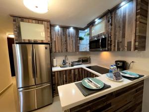 una cocina con nevera de acero inoxidable y armarios de madera en Spacious Retreat with Private Jacuzzi and Terrace, en Ponce