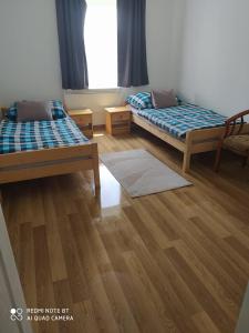 a room with two beds and a wooden floor at Galgavölgye munkásszálló in Aszód
