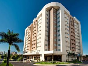 a tall building with a palm tree in front of it at LE JARDIN Suites in Caldas Novas