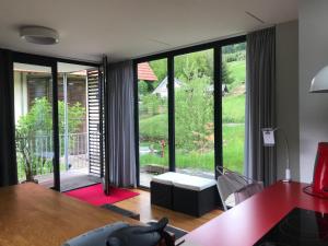 - un salon avec un bureau et une grande fenêtre dans l'établissement S-SUITE das Design-Ferienhaus im Schwarzwald, à Biberach