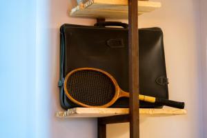 einen Tennisschläger auf einem Regal neben einem Koffer in der Unterkunft Urban Rooms in Taranto