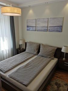uma cama num quarto com 2 almofadas e 2 candeeiros em Dózsa 64 em Dunaújváros