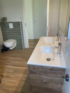 een badkamer met een witte wastafel en een toilet bij Zonnehoeve vakantiehuizen in Hollum