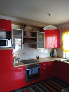 La cuisine est équipée de placards rouges et d'un four avec plaques de cuisson. dans l'établissement APP Margareta, à Umag