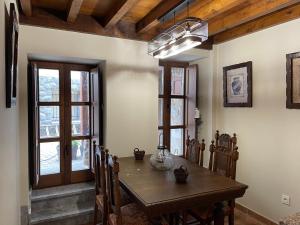 a dining room with a wooden table and some windows at LA CASINA DE PAULA in Ríoseco