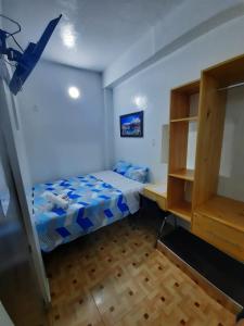 Habitación pequeña con cama y escritorio. en Hostal Estrellas, en Huaraz