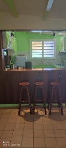 a kitchen with three wooden stools in front of a counter at Concept Kreyol in Sainte-Rose