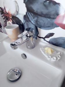 a bathroom sink with a faucet and a cup at B&B Peonia in Porlezza