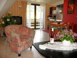 a living room with a chair and a table with a bottle of wine at Gästehaus Bleser in Ernst