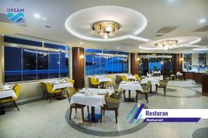 un restaurante con mesas y sillas blancas y ventanas en Zir Dream Thermal & Spa Hotel, en Termal