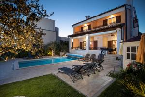 a house with a swimming pool and patio furniture at Villa Suprema Pomer in Pomer
